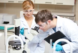 Two scientists observing something with a microscope in their laboratory